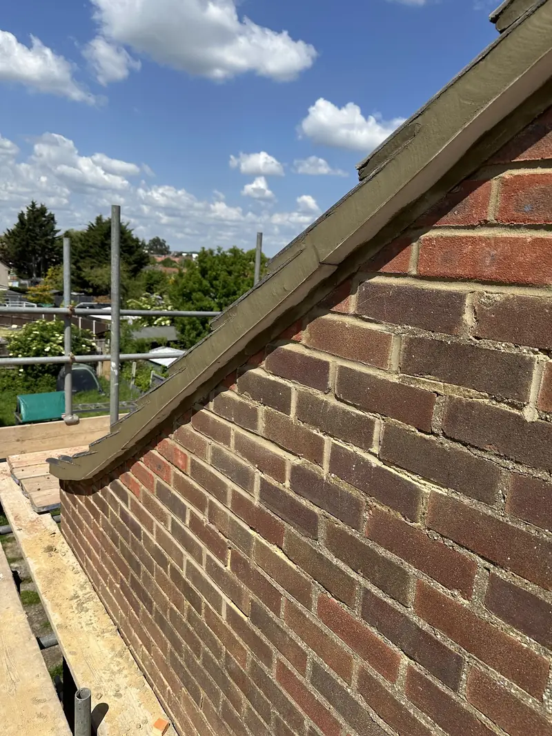 Gable end brickwork and lead flashing under a new roof